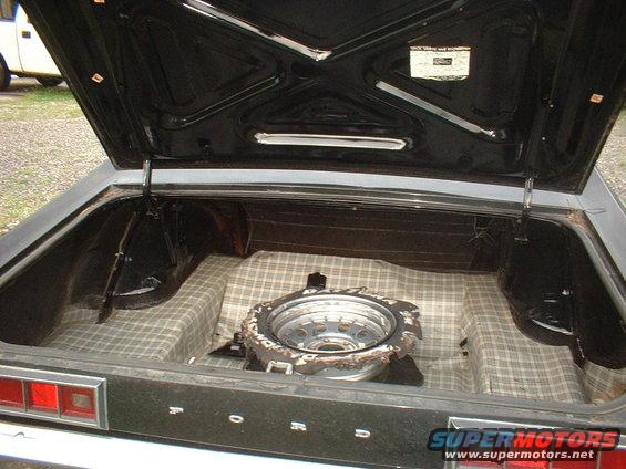 Trunk of a 1970 Ford Falcon showing the spare tire and plaid lining