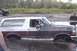 1993 Ford Bronco - A maroon and white Ford Bronco is stuck in the mud with another vehicle in the background.