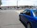 2005 Subaru Impreza - A blue Subaru WRX STI is parked on the street, with a line of police cars in the background.