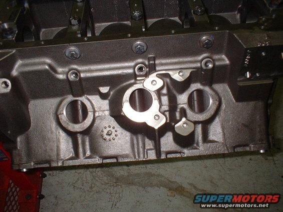 Close-up of a dark gray engine block with circular openings and metal components