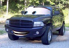 Dark SUV with cartoon eyes on windshield and a big smile on the grille