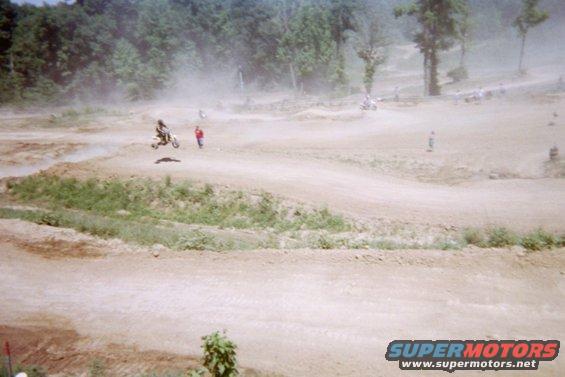 Motocross rider jumps a dirt hill with spectators watching