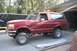 1989 Ford Bronco - This red Ford Bronco features a lifted suspension and aftermarket wheels.