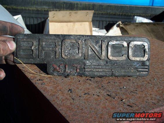 Black Bronco XLT emblem with silver lettering, held by a hand