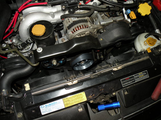 Engine bay with alternator, pulley, and radiator fan. A blue flashlight is visible near the bottom