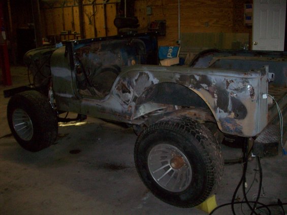 1978 Jeep CJ5 body undergoing restoration, showing rust and primer. Wheels are on, but no engine or interior visible