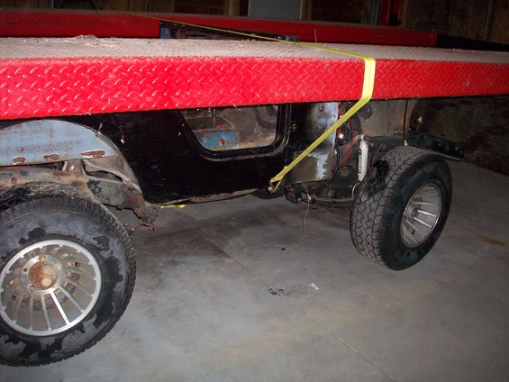 1978 Jeep CJ5 body with black doors and silver wheels, strapped to a red platform