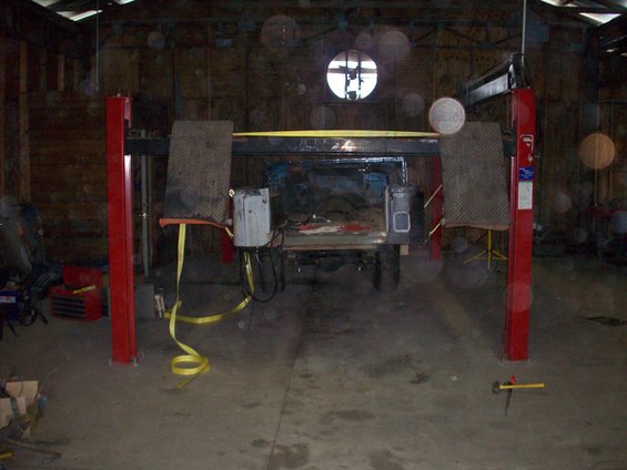 1978 Jeep CJ5 on a red car lift inside a garage, viewed from the rear