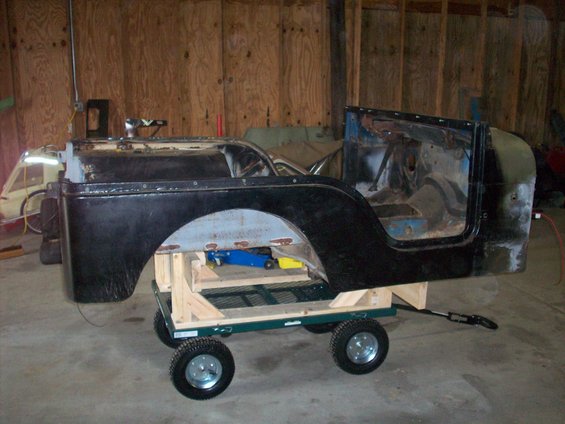 1978 Jeep CJ5 body, black, on a green cart with wooden supports. Interior is visible