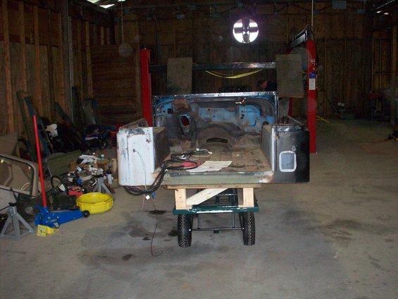Jeep CJ body on a cart in a garage, undergoing restoration