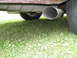 1984 Mercury Grand Marquis - A close-up view of a vehicle's exhaust pipe and tire on a grassy surface.