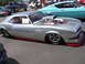 2001 Chevrolet Silverado 1500 - A silver classic car with a prominent hood scoop and racing tires is parked outdoors.