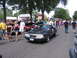 2001 Chevrolet Silverado 1500 - A dark gray 1987 Ford Mustang hatchback is seen at a car show with people and other vehicles around.