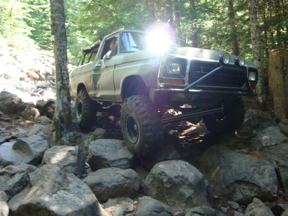 1978 Ford Bronco navigating a rocky trail with large tires and a front brush guard