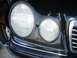 1995 Ford Taurus - The front passenger side headlight assembly of a black Mercedes-Benz E-Class is shown in this close-up view.