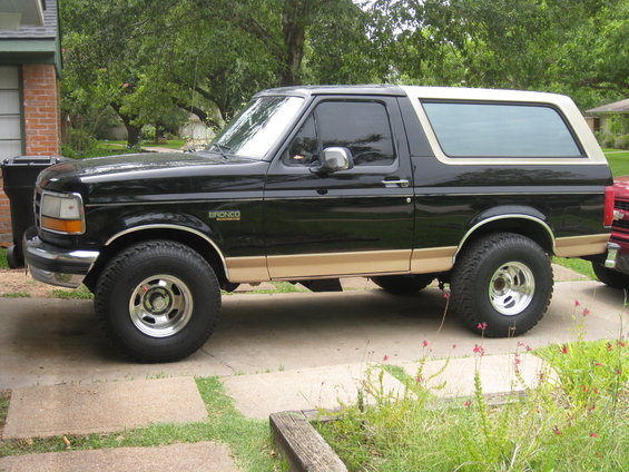 Side view of black Ford Bronco with tan trim and aftermarket wheels