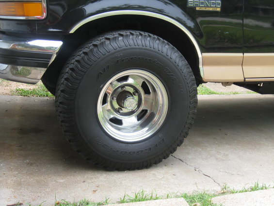 Front wheel and fender of a black and tan Ford Bronco. It has 'All-Terrain T/A' tires