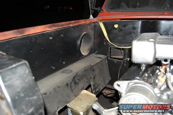 Close-up of engine bay components, showing black metal panels and some engine parts