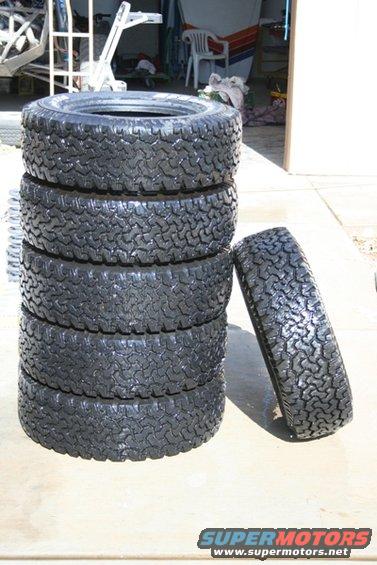 Stack of five off-road tires with one leaning against the stack