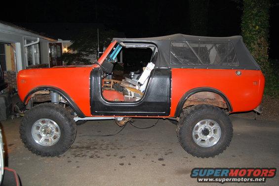 Orange off-road vehicle with black doors and soft top, side view