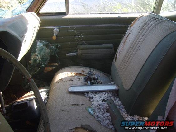 Interior of a car with torn seats, broken windshield, and exposed insulation