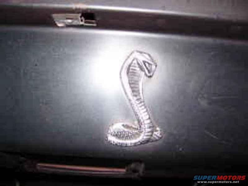 Cobra emblem on dark surface. Supermotors.net logo visible