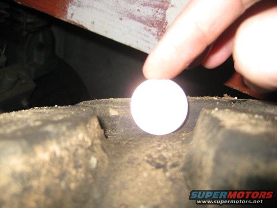 Finger holding a white ball over a tire tread