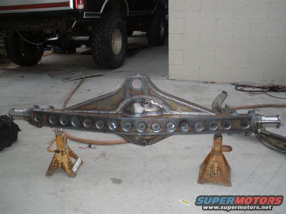 Custom rear axle assembly on jack stands, with a lifted truck in the background