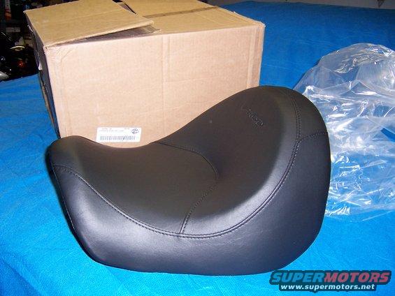 Black motorcycle seat with stitching, next to a cardboard box