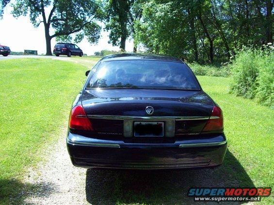 1999 Mercury Grand Marquis rear view, parked on gravel with trees and grass
