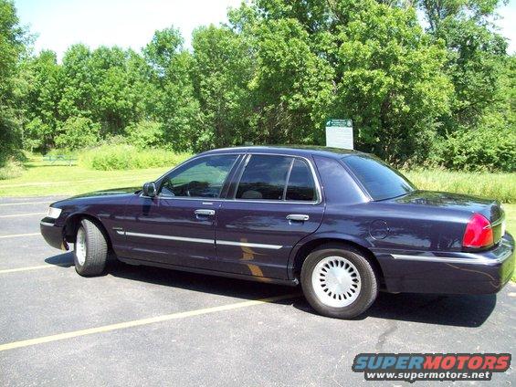 Dark purple sedan parked in a lot with trees in the background