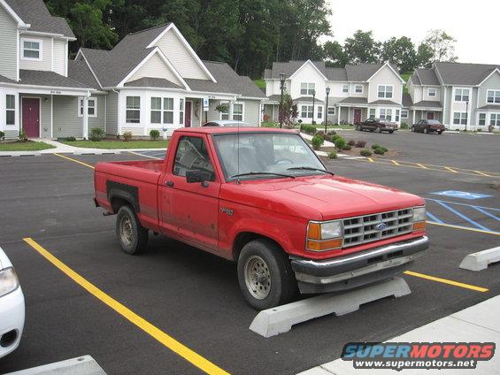 Red 1992 Ford Ranger pickup truck parked in a lot with apartment buildings in the background