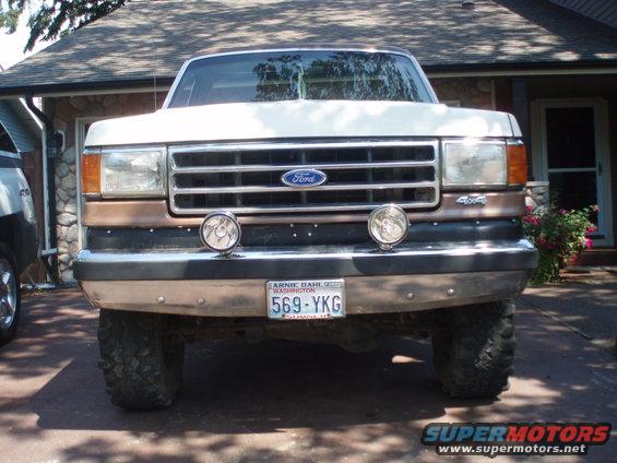 Front view of a white and brown Ford F-Series truck with a chrome grille and '4x4' badge. License plate reads 569-YKG