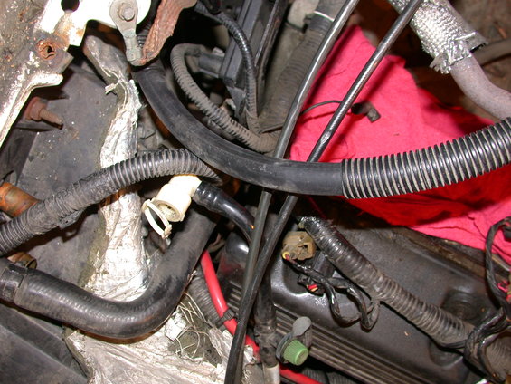 Engine bay with various hoses, wires, and a red cloth