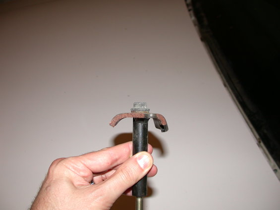 Hand holding a rusty metal clip and bolt assembly