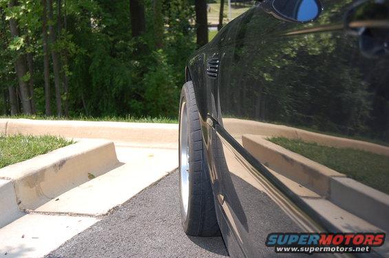 side view of a black car's rear wheel and fender with vents