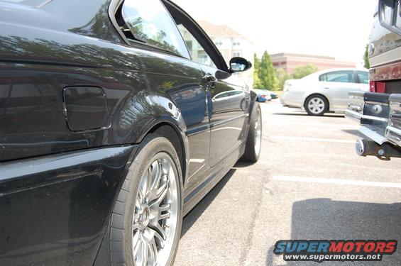 Side view of a black 2002 BMW M3 coupe parked next to a pickup truck