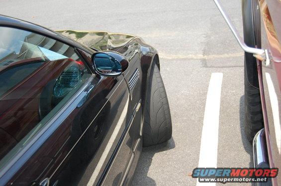 Side view of a black coupe with a fender vent, parked closely next to a maroon vehicle