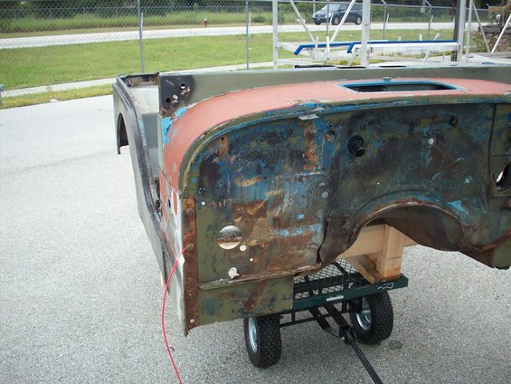 Rusted 1978 Jeep CJ5 body on a green utility cart, showing front fender and cowl area