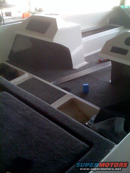 Interior of a boat with carpeted seats and white molded consoles