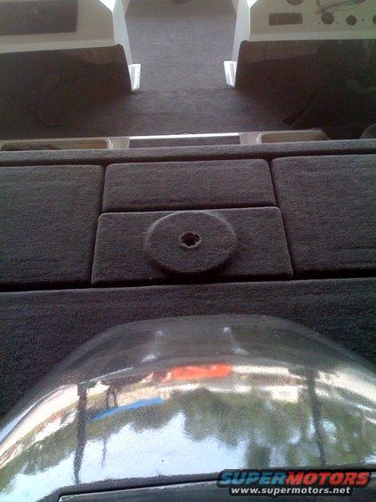 Interior view of carpeted seats and a reflective surface in a vehicle
