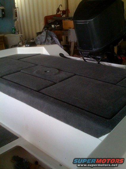 Boat deck with gray carpeted hatches and a black outboard motor in the background