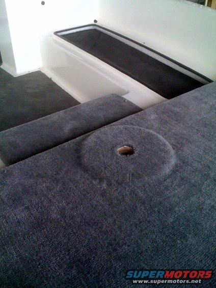 Carpeted interior with a circular cutout and a recessed black area