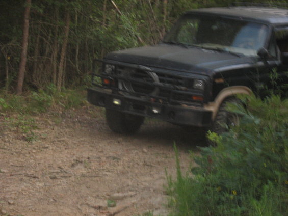 Black SUV with a brush guard and auxiliary lights on a dirt road