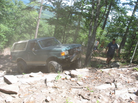 Green SUV with a lifted suspension and off-road tires navigating a rocky trail