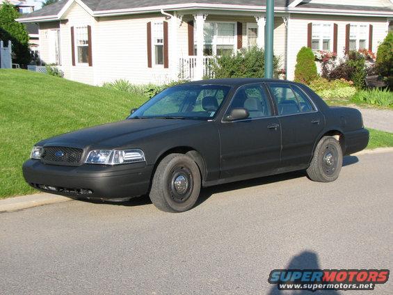 2003 Ford Crown Victoria with matte black paint, parked on a residential street