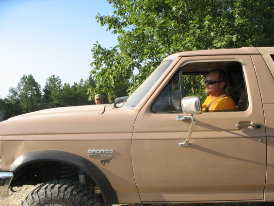Tan Ford Bronco with a man driving, side view