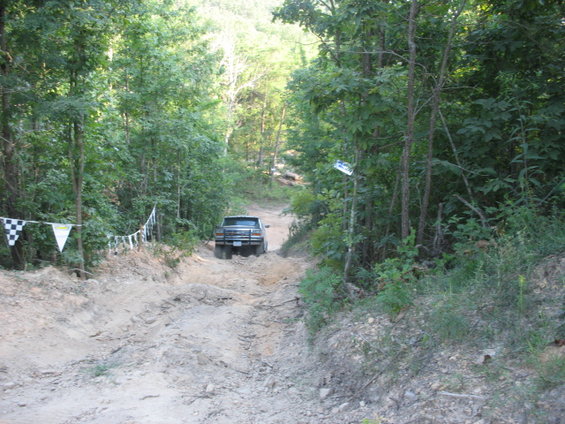 Off-road vehicle driving up a dirt path in a wooded area
