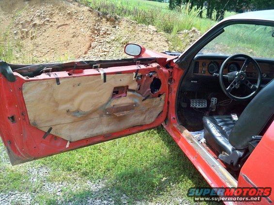 red car interior, door panel removed, showing wiring and insulation