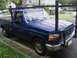 1994 Ford F-250 - A blue Ford F-250 pickup truck with a rack is parked curbside on a residential street.